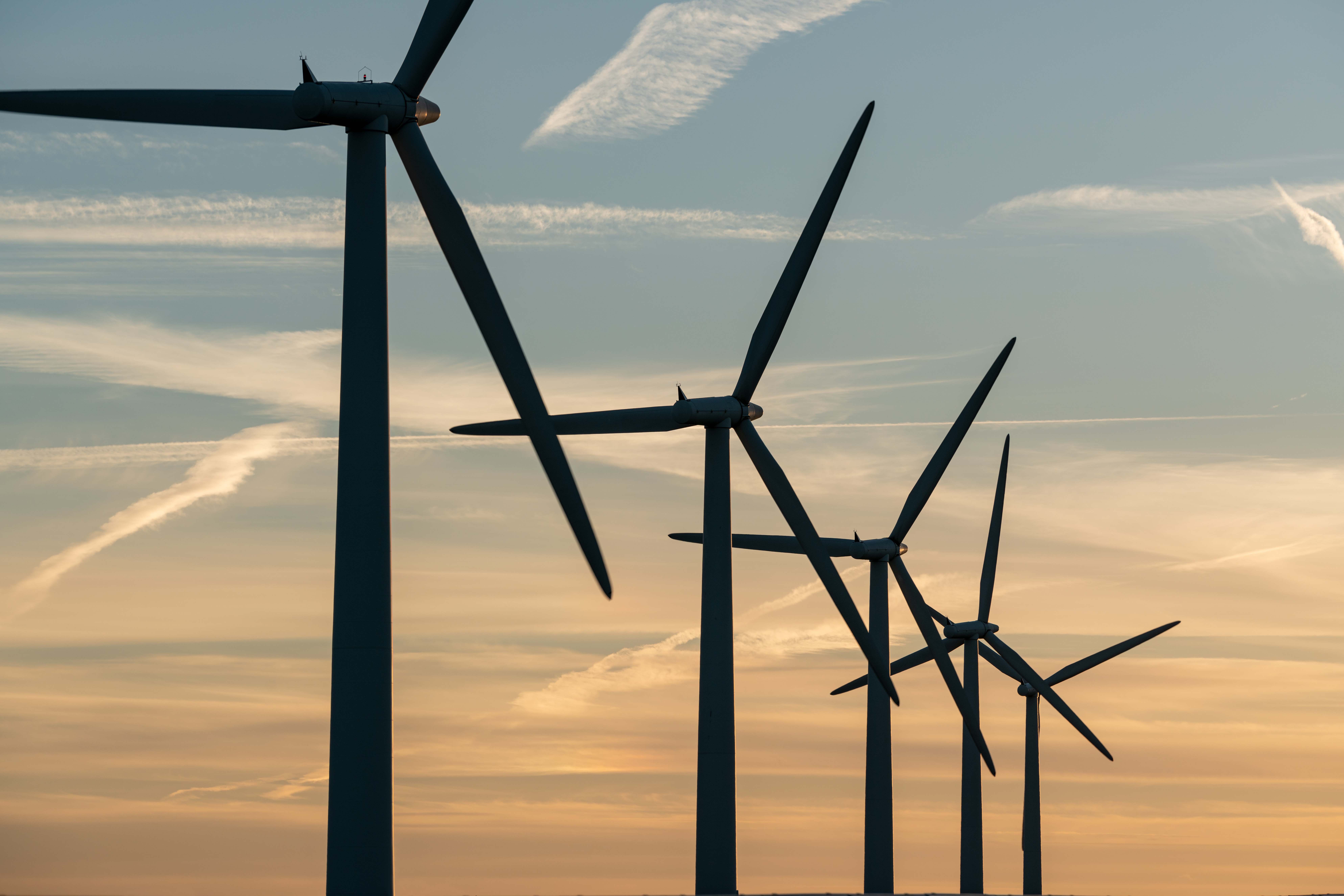 Wind turbines on a green European hillside at golden hour